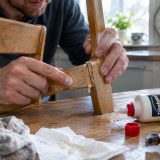 Tube de colle Gorilla jaune et noir posé sur une surface de travail propre à côté de deux pièces de bois assemblées avec des serre-joints